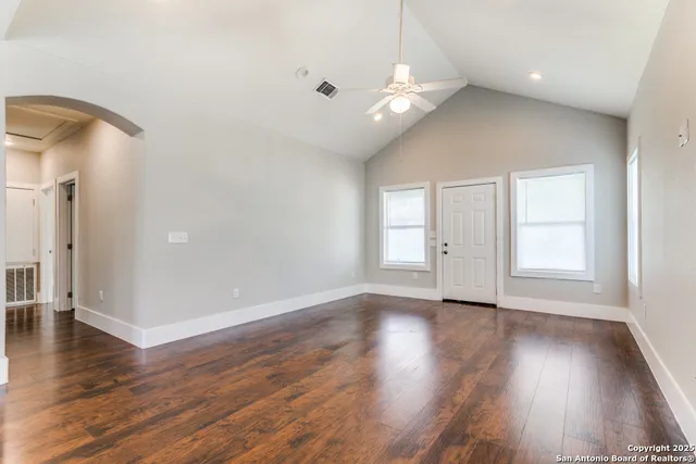 a view of an empty room with wooden floor and a window