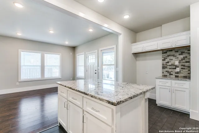 a kitchen with kitchen island granite countertop a stove and a sink