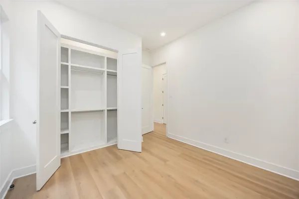 a view of an empty room with wooden floor and closet