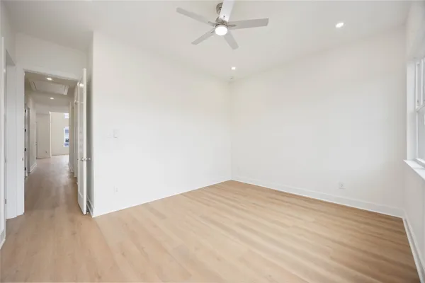 an empty room with wooden floor and fan