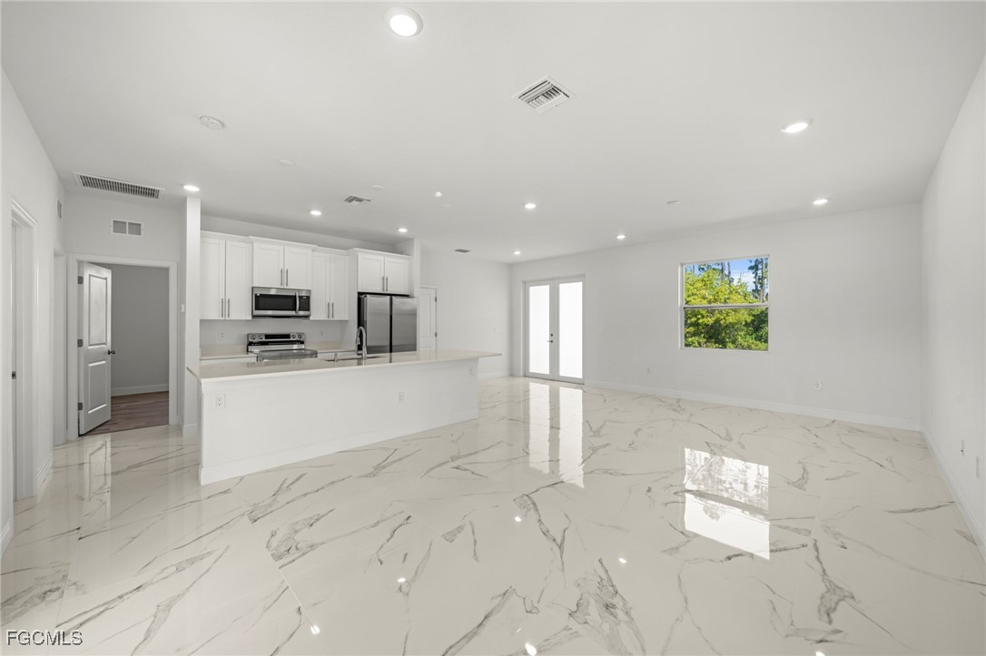 1252 Edna Street East Lehigh Acres, FL 33974 - Photo 6 of 25 a view of kitchen with kitchen island white cabinets and refrigerator
