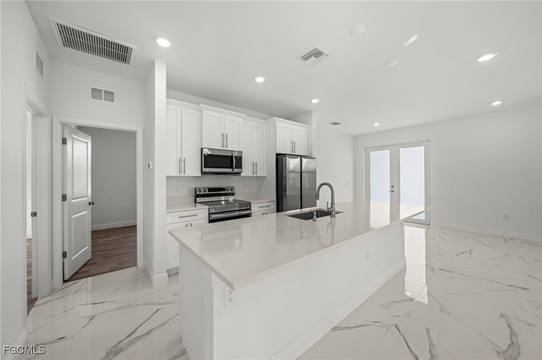 1252 Edna Street East Lehigh Acres, FL 33974 - Photo 7 of 25 a kitchen with stainless steel appliances a refrigerator and a stove top oven