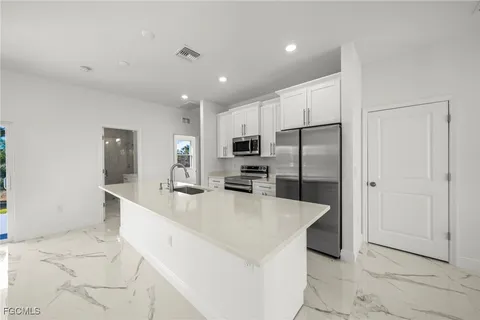a large kitchen with stainless steel appliances kitchen island a large counter top and a refrigerator