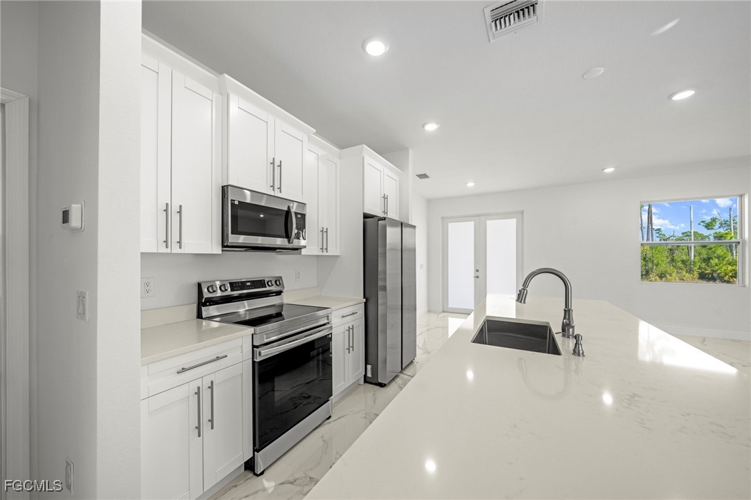 1252 Edna Street East Lehigh Acres, FL 33974 - Photo 9 of 25 a kitchen with stainless steel appliances a sink stove and refrigerator