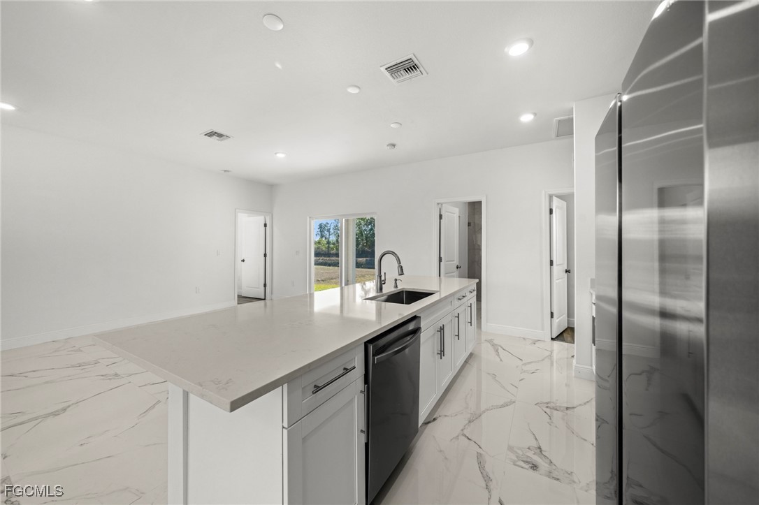 1252 Edna Street East Lehigh Acres, FL 33974 - Photo 10 of 25 a kitchen with stainless steel appliances granite countertop a sink and a refrigerator