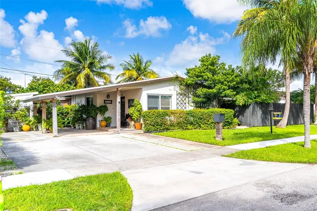 a view of a house with a yard and palm trees