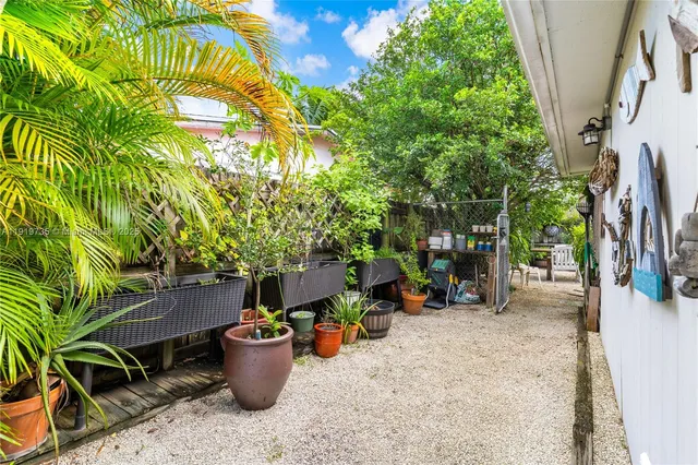 a view of a backyard with table and chairs potted plants and large tree