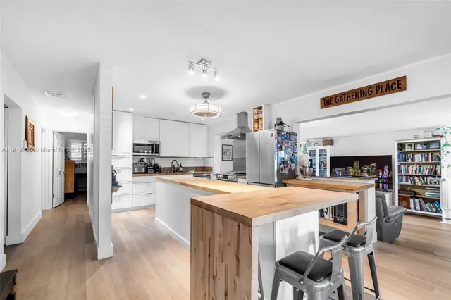 a open kitchen with stainless steel appliances kitchen island granite countertop a table chairs and a refrigerator