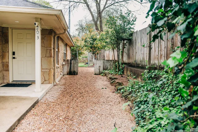 a living room with furniture a potted plant and open kitchen view