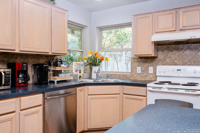 a kitchen with granite countertop a sink stainless steel appliances and cabinets