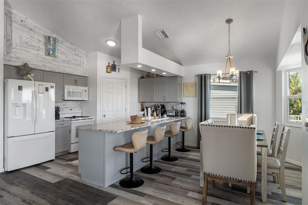 4046 Casa Court Hernando Beach, FL 34607 - Photo 11 of 58 a kitchen with stainless steel appliances granite countertop a refrigerator a stove a sink dishwasher a dining table and chairs with wooden floor