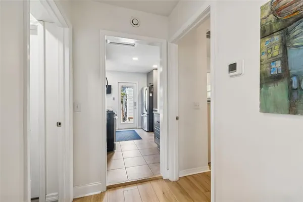a kitchen with stainless steel appliances granite countertop a stove top oven a sink a refrigerator and white cabinets with wooden floor