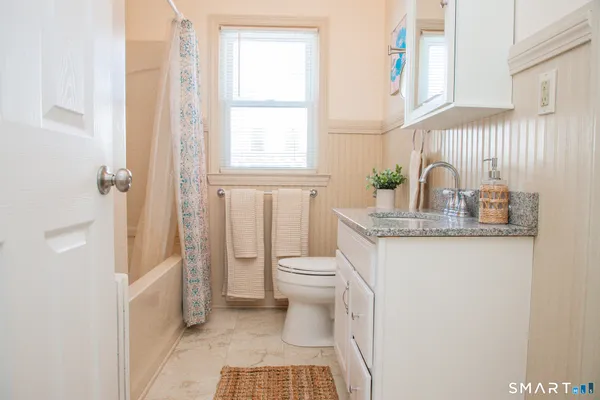 a bathroom with a granite countertop sink a toilet and a window