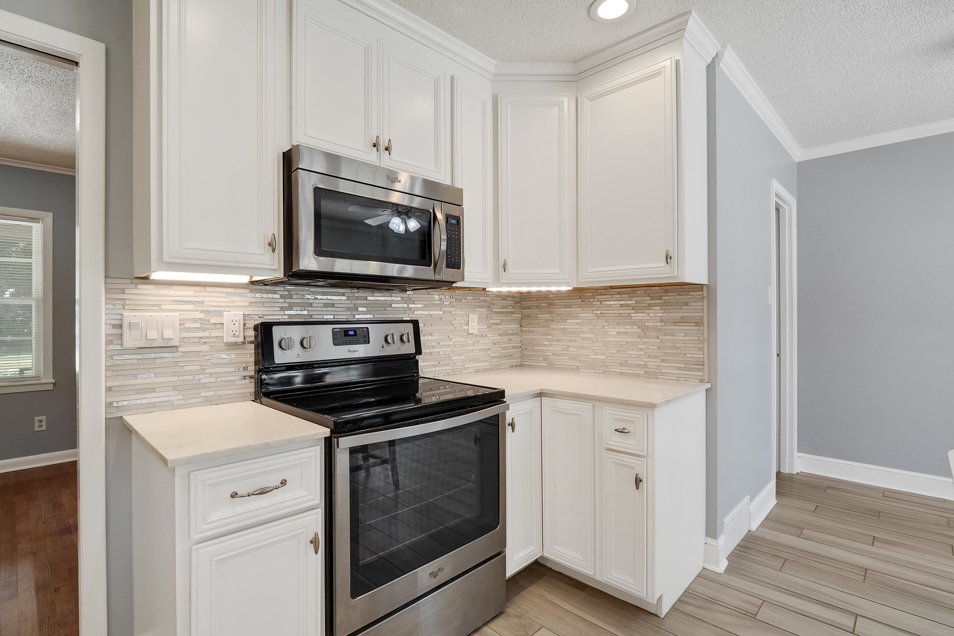 1551 Delmont Road Memphis, TN 38117 - Photo 11 of 25 a kitchen with cabinets stainless steel appliances and a wooden floor