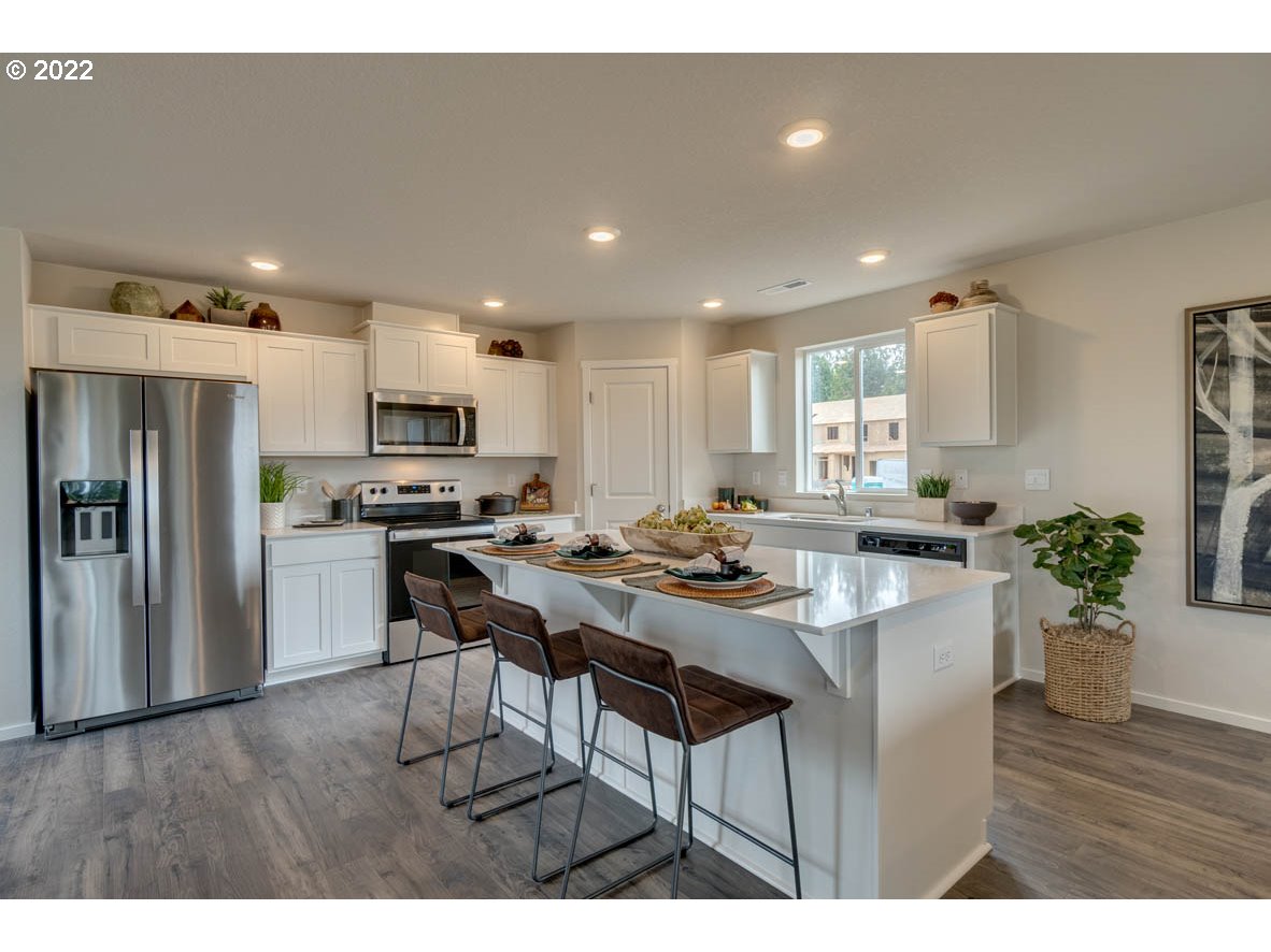 2914 North 3rd Way Ridgefield, WA 98642 - Photo 4 of 24 a kitchen with stainless steel appliances kitchen island granite countertop a refrigerator a stove a sink dishwasher and a dining table with wooden floor
