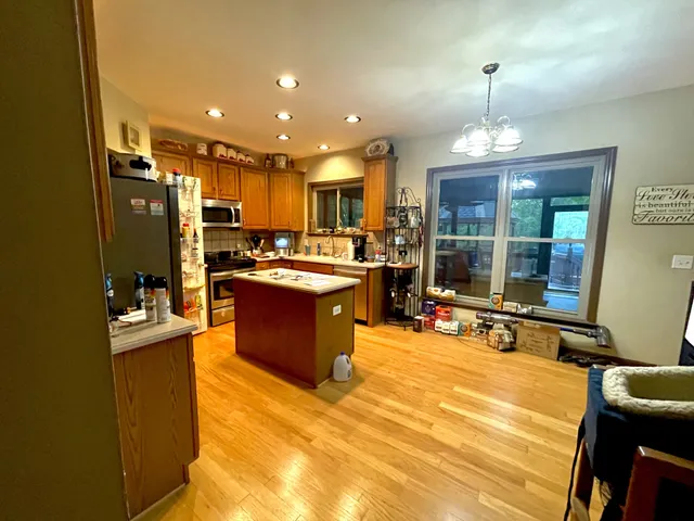 a view of a kitchen with stainless steel appliances granite countertop a stove top oven a sink dishwasher a dining table and chairs with wooden floor