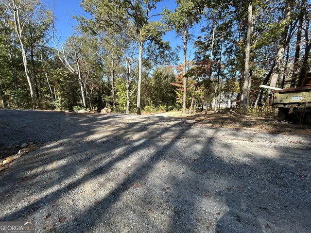 a backyard of a house with large trees and wooden fence