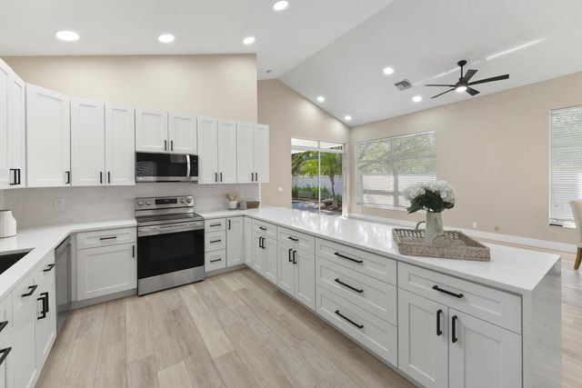 a large white kitchen with stainless steel appliances granite countertop a stove a sink dishwasher and a oven with white cabinets