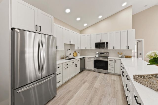 a kitchen with granite countertop a refrigerator a sink dishwasher and a stove with wooden floor