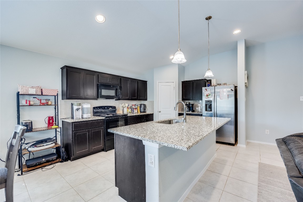 21302 Santa Rosa Avenue Lago Vista, TX 78645 - Photo 11 of 26 a kitchen with kitchen island granite countertop a stove oven and a sink with cabinets