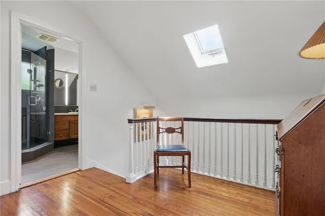 a view of a hallway with wooden floor and a bathroom