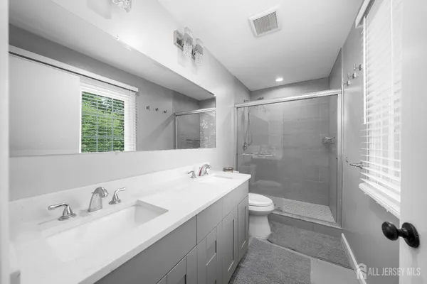 a bathroom with a double vanity sink toilet and shower