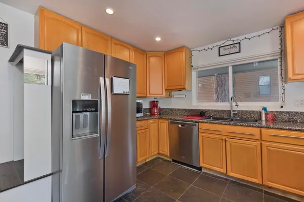 a kitchen with a sink a counter top space stainless steel appliances cabinets and a large window