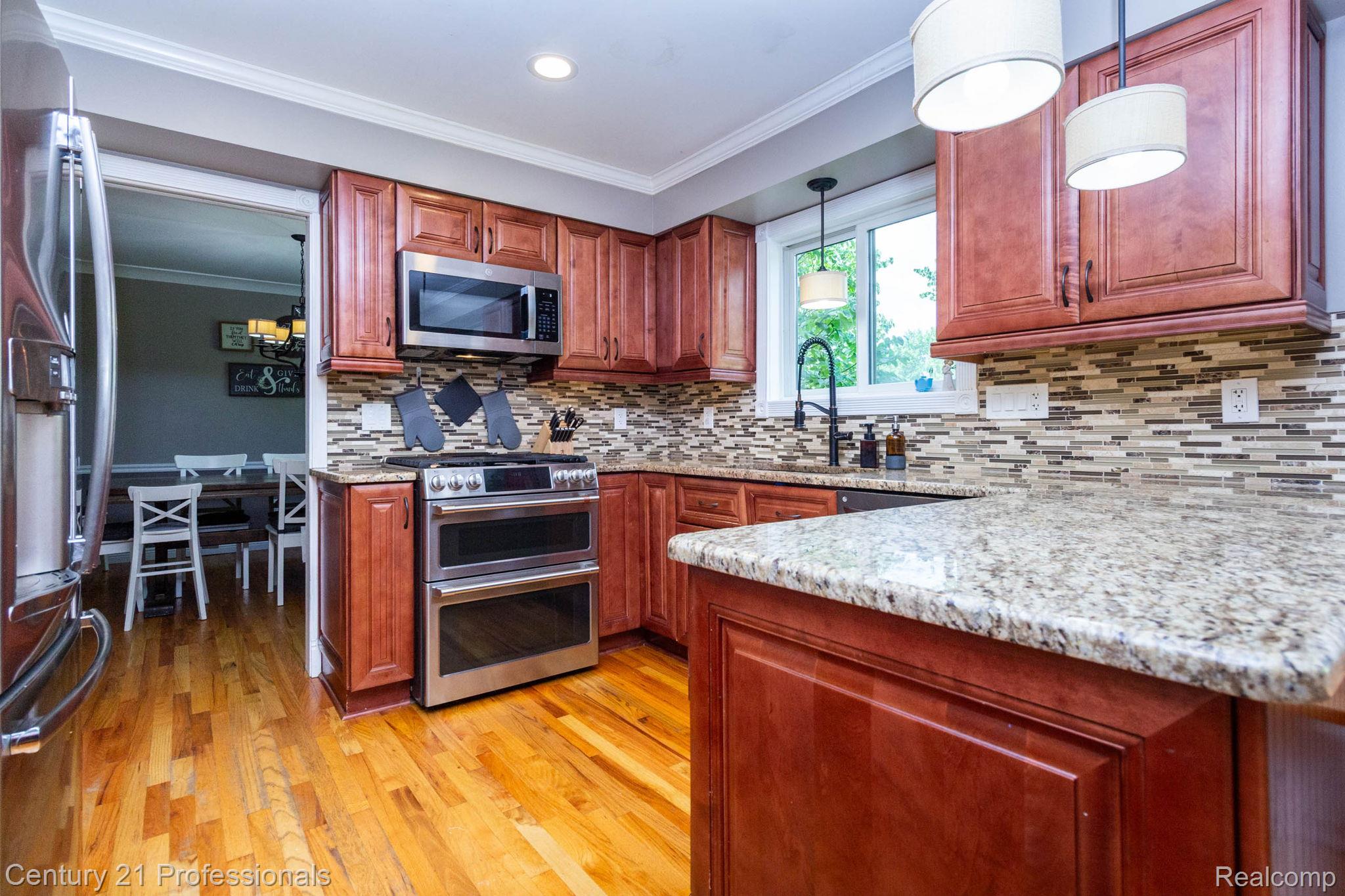 671 Bridgestone Drive Rochester, MI 48309 - Photo 13 of 50 Gourmet kitchen featuring wood-finish flooring, granite countertops, and a full tile backsplash