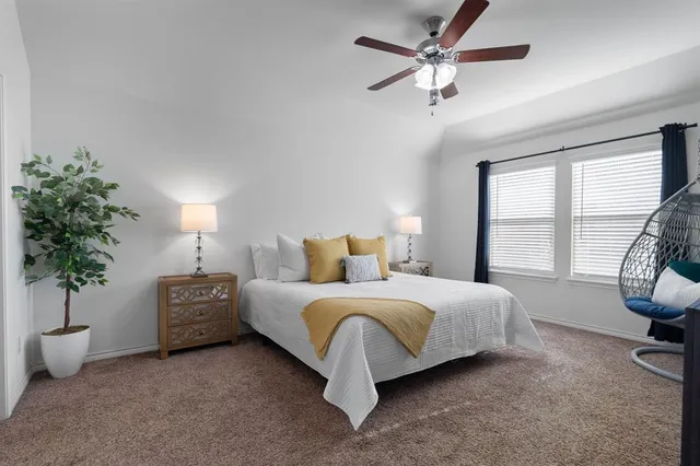 a spacious bedroom with a bed a couch and a potted plant