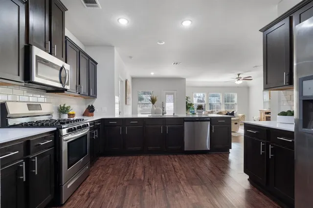 a large kitchen with stainless steel appliances and wooden cabinets