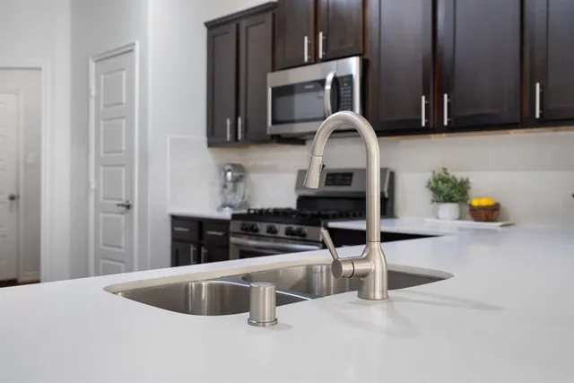 a kitchen with stainless steel appliances granite countertop a sink a microwave cabinets and a counter top space