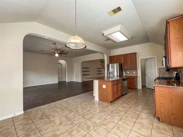 a large kitchen with kitchen island granite countertop a stove a sink a refrigerator and a granite counter top