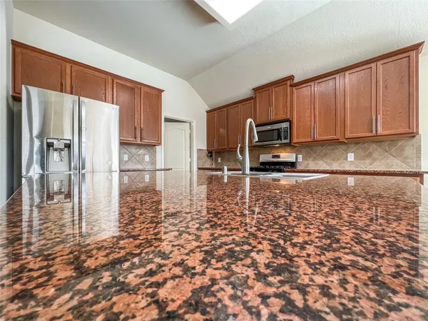 a kitchen with granite countertop a refrigerator a stove top oven a sink and dishwasher