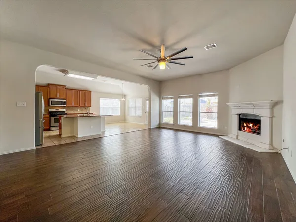a view of an empty room with wooden floor and a fireplace
