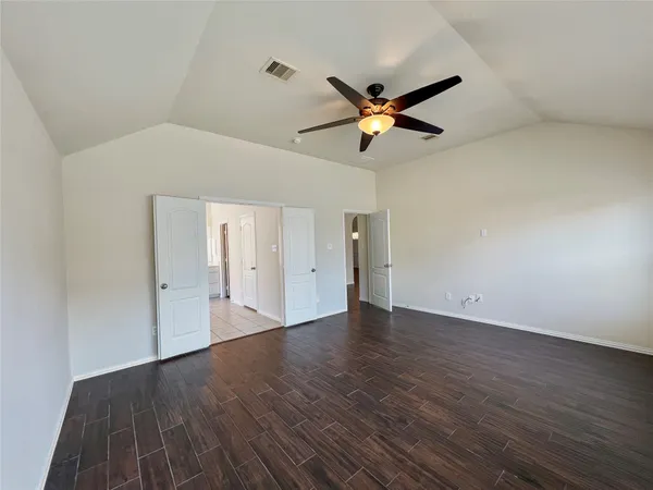 an empty room with wooden floor and windows