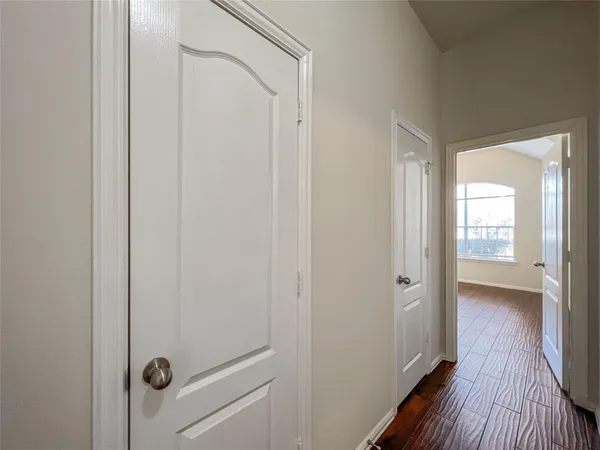 a view of a hallway with wooden floor and a bathroom