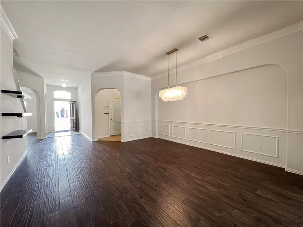 a view of an empty room with wooden floor and window