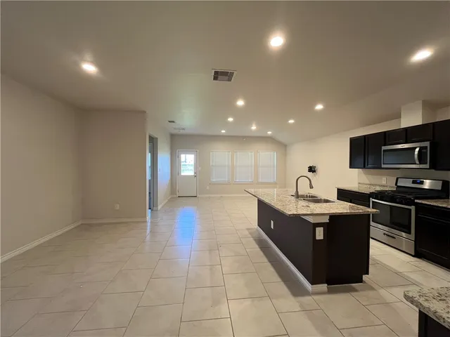 a large kitchen with stainless steel appliances granite countertop a sink and cabinets
