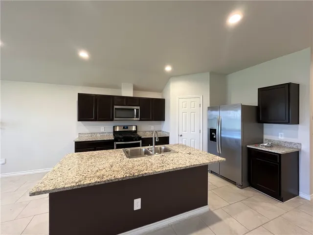 a kitchen with stainless steel appliances granite countertop a sink and a refrigerator