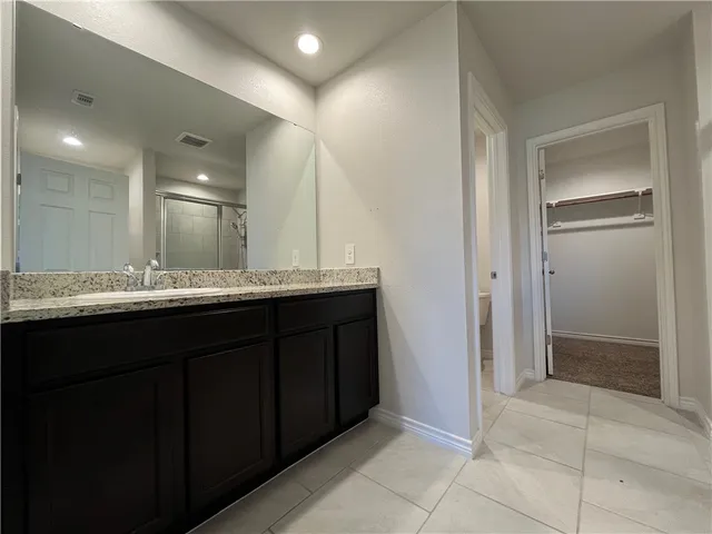 a bathroom with a granite countertop sink a mirror and a shower