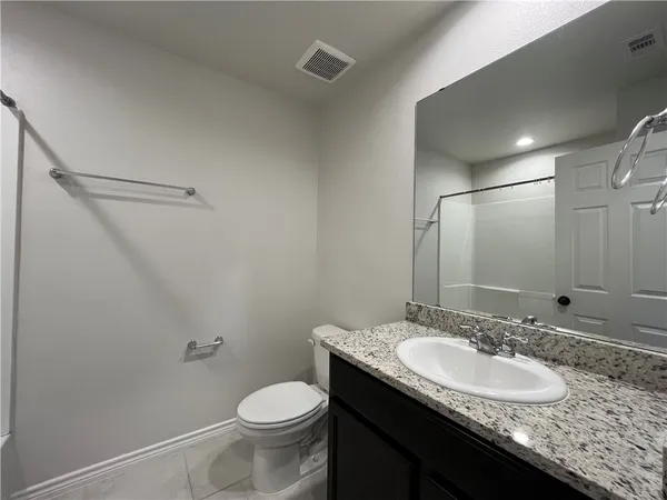 a bathroom with a granite countertop sink a toilet and a mirror