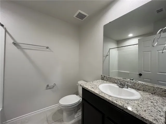 a bathroom with a granite countertop sink a toilet and a mirror