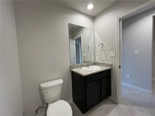 a bathroom with a granite countertop sink and a toilet