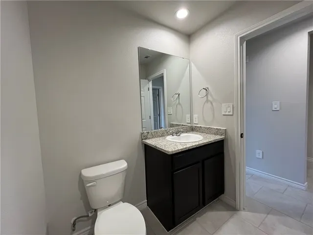 a bathroom with a granite countertop sink and a toilet