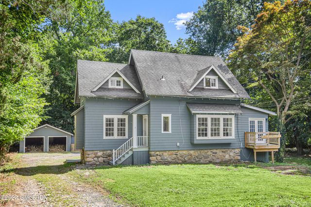 a view of a yard in front of a house with large windows
