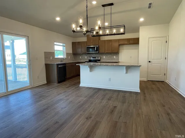 a large kitchen with stainless steel appliances granite countertop a large island in the center and wooden floors