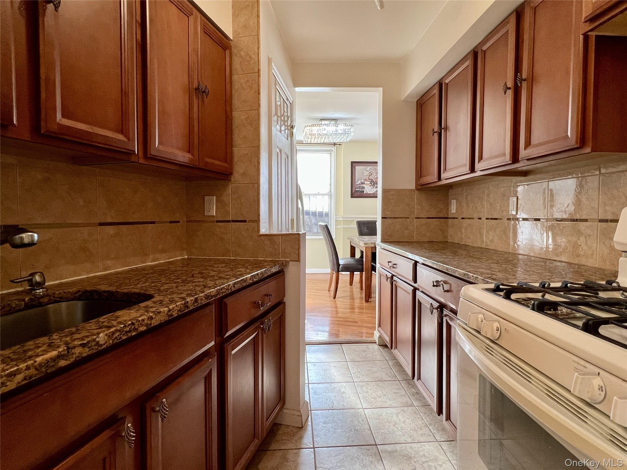 86-16 60th Avenue, Unit 2D Queens, NY 11373 - Photo 14 of 30 a kitchen with stainless steel appliances granite countertop a stove a sink dishwasher and cabinets with wooden floor