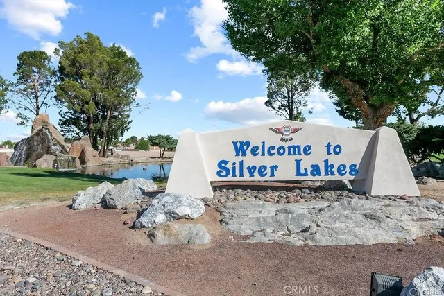 a view of a sign board with yard and trees