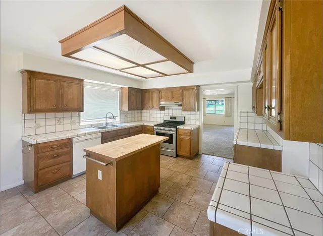 a kitchen with stainless steel appliances granite countertop a stove top oven a sink a counter top space and cabinets