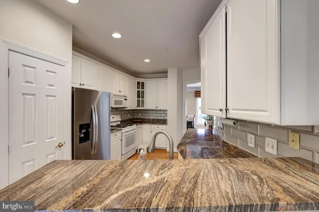 a large kitchen with stainless steel appliances granite countertop a refrigerator and a stove top oven